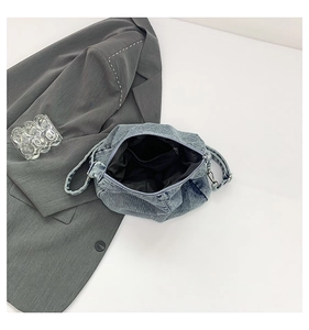 Detail of the blue denim shoulder bag showing black fabric lining and zippered pocket