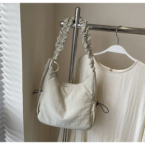 Detailweergave van beige cloud bag met trekkoorden aan de zijkant en gewatteerd nylon