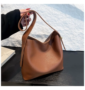 Close-up of brown textured leather bucket bag with wide strap for casual daily use