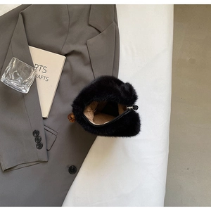 Detailed top view of black faux fur bag with soft plush texture and amber cylinder charm