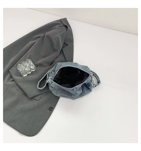 Detailed macro view of the light blue denim shoulder bag with secure metal zipper closure