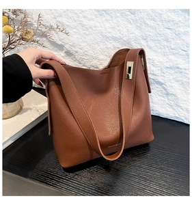 Detail of dark brown leather tote with荔枝 texture and gold hardware connector