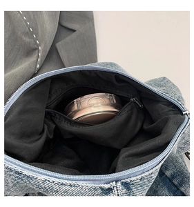 Detail view of denim tote bag interior showing black lining and hidden zipper pocket
