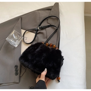 Detail of black faux fur handbag featuring unique amber beaded handle and leather strap