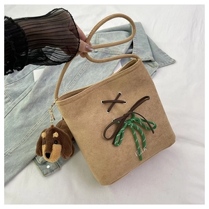 Detail of a beige suede bucket bag with Villa embroidery and a brown puppy keychain