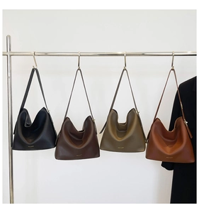 Detail view of large Hobo tote bags in black, brown, and green on a minimalist silver rack