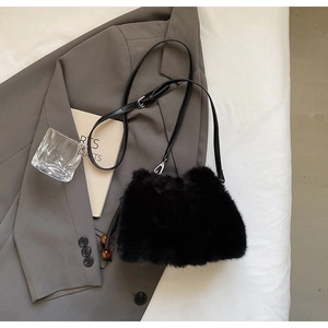 Detail of black faux fur bucket bag featuring a brown bead charm on a grey blazer