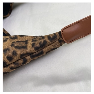 Detailed close-up of leopard print fabric texture and brown leather strap stitching