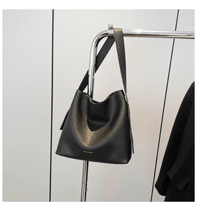 Detail view of the black leather bucket bag featuring a gold artistic gradient texture