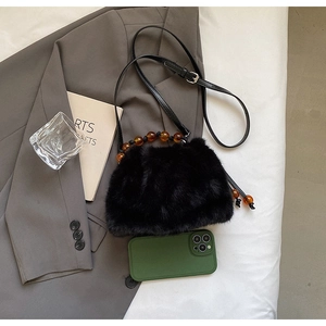 Detail of black faux fur bucket bag with amber bead accents and adjustable strap