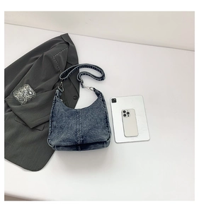 Top view of blue denim hobo bag with printed strap near a blazer and a tablet