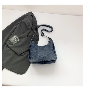Detail of dark blue denim crescent bag with vintage faded texture and silver zipper