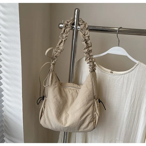 Detail van beige nylon wolktas met geplooide schouderband en zijdelings trekkoord-accent