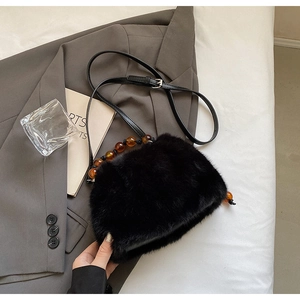 Detail of black faux fur bag featuring an amber beaded handle and long plush texture
