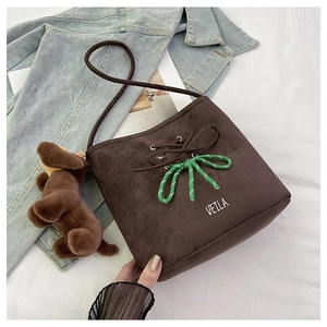 Detail of suede bucket bag featuring contrast green woven knot and brown leather tie