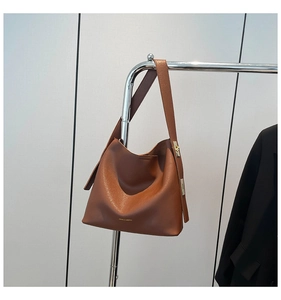 Close-up of brown pebbled leather bucket bag with gold hardware and branding on white background