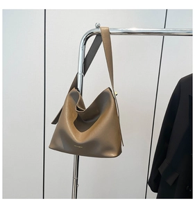 Detail of matte brown leather hobo bag showing fine texture and golden logo on a metal rack