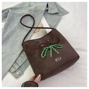 Detail of dark brown suede bucket bag featuring striped rope knot and VELLA branding