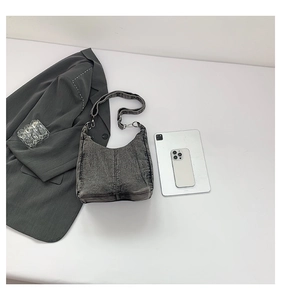Detailed overhead view of washed gray denim hobo bag with topstitching and wide strap