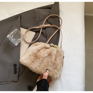 Detail view of khaki faux fur bucket bag featuring light green beaded handle and strap