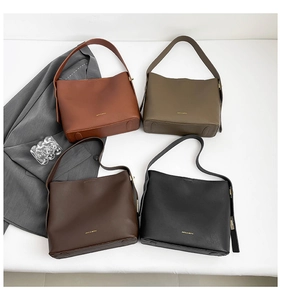 Flat lay of four minimalist leather bucket bags in brick red, brown, and black colors
