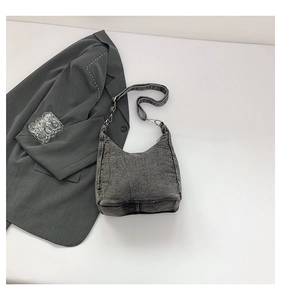 Detail of grey washed denim hobo bag featuring vintage texture and adjustable strap