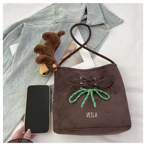 Detail of dark coffee suede bucket bag with green woven bow and plush dog charm