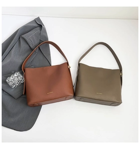 Close-up of minimalist brown and olive green faux leather hobo bags with golden brand logo