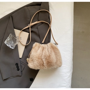 Detailed shot of beige faux fur crossbody bag with pearl charm and leather strap