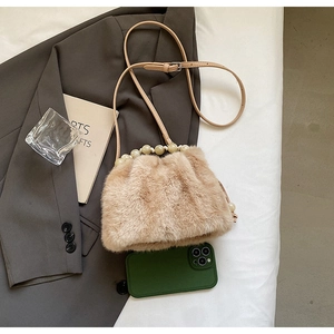 Detailed view of beige faux fur bucket bag with pearl handle and leather strap
