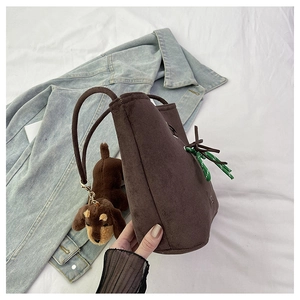 Detail of suede bucket bag featuring woven rope accent and cute dog plush charm