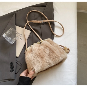 Detail of light brown faux mink fur crossbody bag with cream bead trim and leather strap