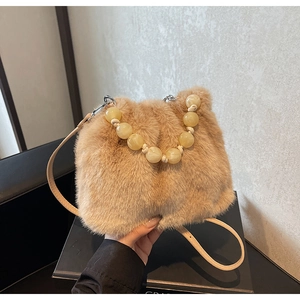 Detailed shot of faux fur handbag with amber bead handle and leather strap in camel color