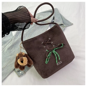 Detail of a brown suede bucket bag with green cord knot and cute dog plush pendant