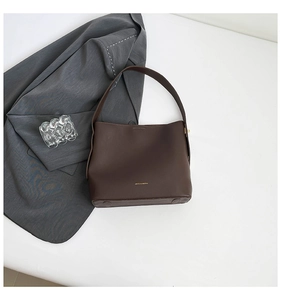 Close-up of the vintage coffee brown leather bucket bag with gold logo and wide strap