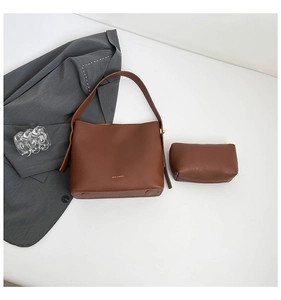 Close-up of dark brown leather bucket bag set with gold logo and fine stitching details