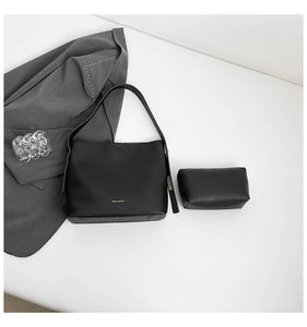 Detail view of black faux leather bucket bag and pouch set with gold lettering