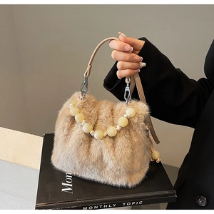 Detail of camel faux fur bucket bag featuring plush texture and ivory beaded chain decor