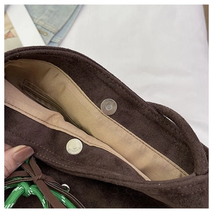 Detailed view of dark brown suede bucket bag with magnetic closure and woven rope detail