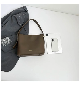 Detail view of khaki bucket bag showing gold brand lettering and anti-wear bottom studs