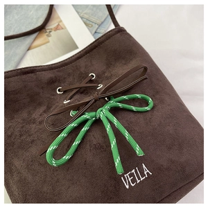 Close-up of brown suede bucket bag featuring green woven rope and logo embroidery
