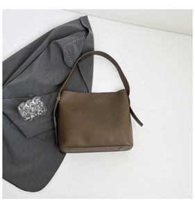 Detail view of the brown leather bucket bag with wide strap and anti-wear bottom studs