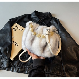 Detail of grey faux mink bucket bag featuring amber beaded handle and leather strap