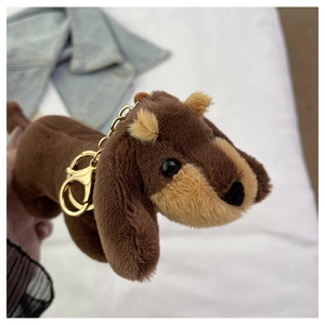 Detail of dachshund plush keychain with golden metal clip on denim background