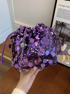 Borsa a secchiello viola con paillettes e catena d'argento portata da una modella