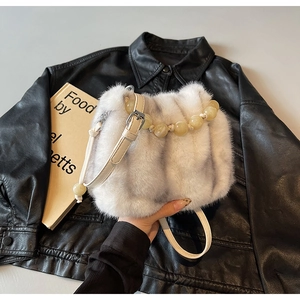 Close-up of faux fur crossbody bucket bag with amber bead handle and leather strap