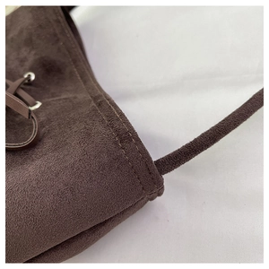 Detailed view of dark brown faux suede bucket bag with meticulous stitching and eyelets