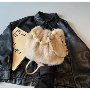 Detail of faux mink bucket bag featuring a beaded handle and plush beige texture