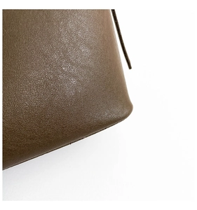 Close-up detail of premium brown lychee pattern leather texture on a bucket bag