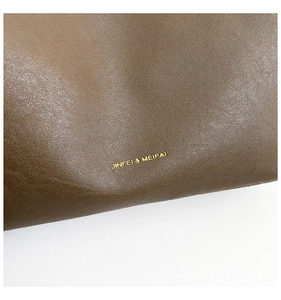 Detailed close-up of brown textured leather surface with elegant gold metallic logo